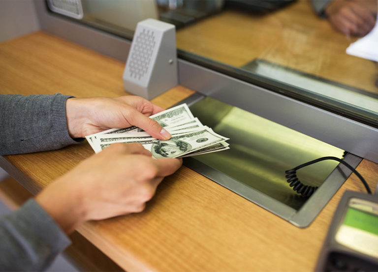person handing money to bank teller